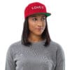 Woman wearing a red cap with "LOVE IS."