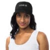 Woman wearing a black cap with "Love Is."