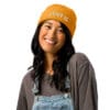 Smiling person wearing a yellow knit beanie.
