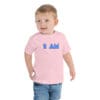 Child wearing pink shirt with "I AM" text.
