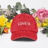 Red cap with "LOVE IS" embroidered text.
