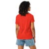 Woman wearing a red shirt and denim shorts.
