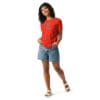 Woman in red t-shirt and denim shorts.